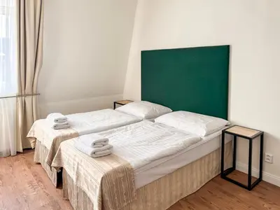 two beds in a room with a green headboard at Hotel Malá Strana in Prague