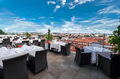 a restaurant with tables and chairs and a view of the city at Golden Well in Prague