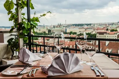 a table with wine glasses and a view of the city at Golden Well in Prague