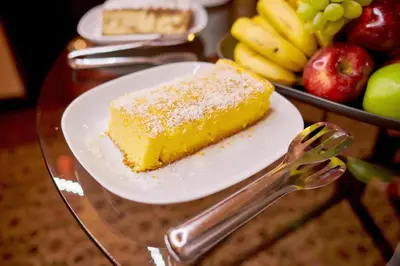 a piece of cake on a plate next to a tray of fruit at La Boutique in Prague