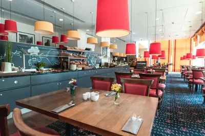 a restaurant with a wooden table and red chairs at OREA Hotel Angelo Praha in Prague