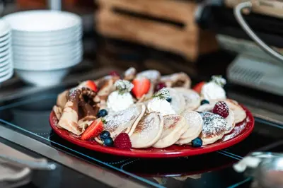 a red plate of pastries with fruit and whipped cream at OREA Hotel Angelo Praha in Prague