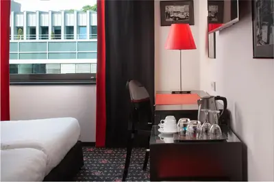 a hotel room with a bed and a desk and a table with a lamp at OREA Hotel Angelo Praha in Prague