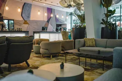 a lobby with couches and tables and a bar at OREA Hotel Angelo Praha in Prague