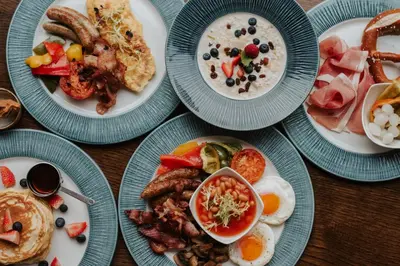 a table with plates of breakfast food on it at OREA Hotel Angelo Praha in Prague