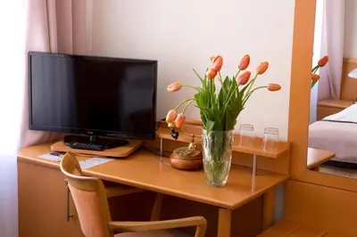 a desk with a computer and a vase of flowers on it at Máchova in Prague