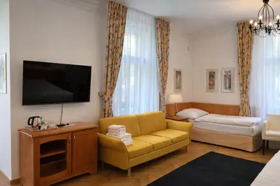a living room with a yellow couch and a television at Residence Dykova - former Pension Jana, Domov Mládeže in Prague
