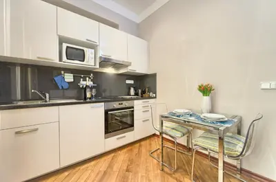 a kitchen with white cabinets and a table with chairs at Residence Masna in Prague