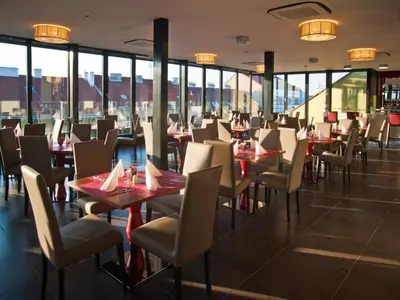 a dining room with tables and chairs and windows at Hotel Galileo in Prague