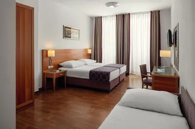 a hotel room with two beds and a desk at Hotel Galileo in Prague