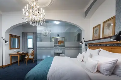 a bedroom with a bed and a desk and a chandelier at Monastery Garden Prague in Prague