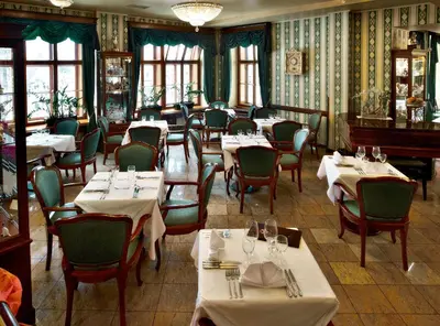 a restaurant with tables and chairs and windows at Grand Hotel Praha in Prague