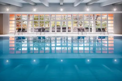 a swimming pool with chairs in a building at Hotel Duo & Wellness in Prague
