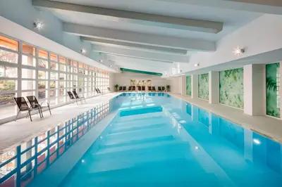 an indoor swimming pool with blue water in a building at Hotel Duo & Wellness in Prague