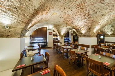 a restaurant with tables and chairs and a stone ceiling at Archibald At the Charles Bridge in Prague