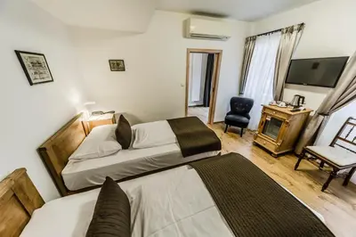 a bedroom with two beds and a television and a chair at Archibald At the Charles Bridge in Prague