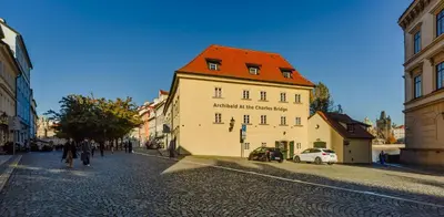 a large white building with a red roof on a street at Archibald At the Charles Bridge in Prague