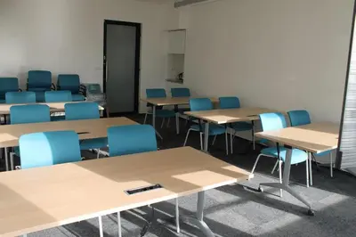 an empty classroom with desks and blue chairs at Akcent hotel in Prague