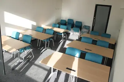 a classroom with wooden tables and blue chairs at Akcent hotel in Prague