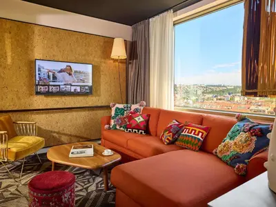 a living room with a couch and a large window at Mama Shelter Prague in Prague