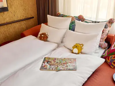 two stuffed animals sitting on a bed with pillows at Mama Shelter Prague in Prague