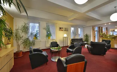 a waiting room with chairs and tables and plants at EA Hotel Populus in Prague