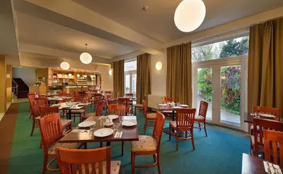 a restaurant with wooden tables and chairs and windows at EA Hotel Populus in Prague