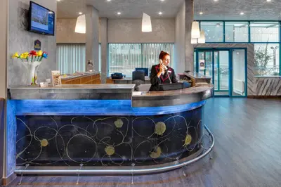 a woman sitting at a reception desk in a lobby at Amedia Express Prague, Trademark Collection by Wyndham in Prague