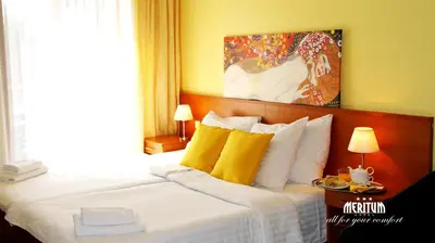 a hotel room with a large bed with yellow pillows at Hotel Meritum in Prague