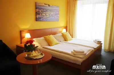 a bedroom with a bed with a table and a window at Hotel Meritum in Prague