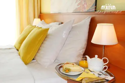 a bed with a table with a plate of food on it at Hotel Meritum in Prague