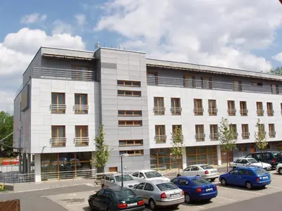 a large white building with cars parked in a parking lot at Hotel Meritum in Prague