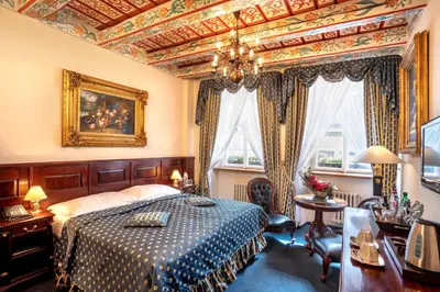 a bedroom with a bed and a chandelier at Hotel U Zlatého Stromu Prague by BHG in Prague