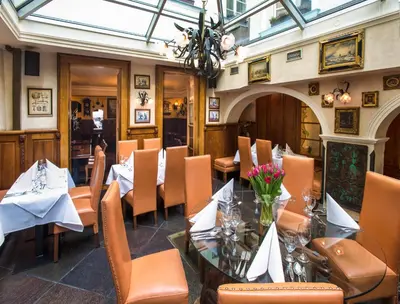 a dining room with tables and chairs and a chandelier at Hotel U Zlatého Stromu Prague by BHG in Prague