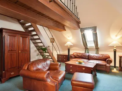 a living room with leather furniture and a staircase at Hotel U Zlatého Stromu Prague by BHG in Prague