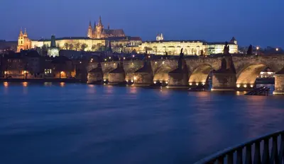 a bridge over a river with a city at night at Occidental Praha in Prague