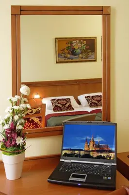 a laptop computer sitting on a desk next to a bedroom at Green Garden Hotel in Prague