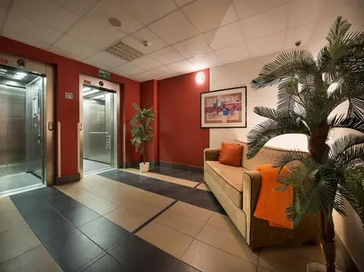 a waiting room with a couch and a palm tree at Rezidence Emmy in Prague
