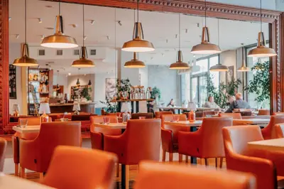 a restaurant with tables and chairs and pendant lights at Plaza Boutique Hotel - Czech Leading Hotels in Prague