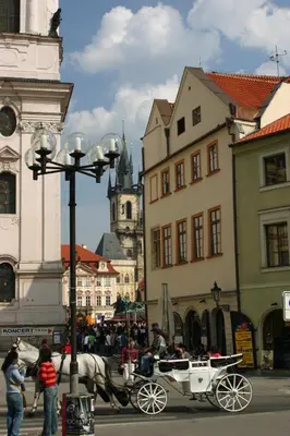 a horse drawn carriage on a city street with buildings at U Tří Bubnů in Prague