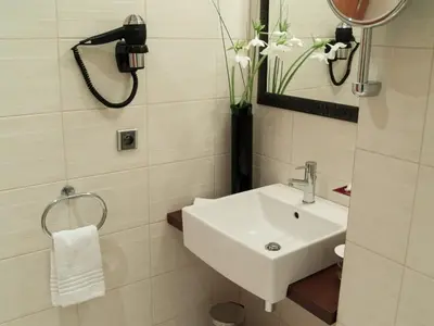 a white bathroom with a sink and a mirror at Design Merrion Residence in Prague