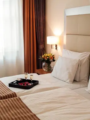 a hotel room with a tray of wine glasses on a bed at Design Merrion Residence in Prague