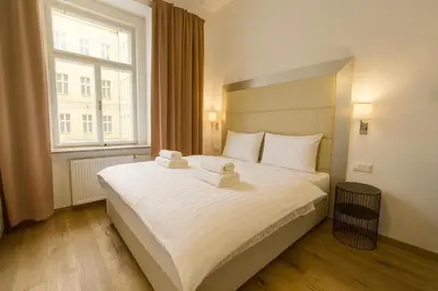 a bedroom with a large white bed with a window at Design Merrion Residence in Prague