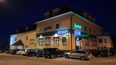a large building with cars parked in front of it at Hotel Tulipan Pruhonice in Pruhonice