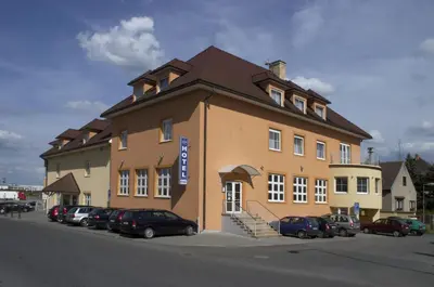 a large building with cars parked in front of it at Hotel Tulipan Pruhonice in Pruhonice