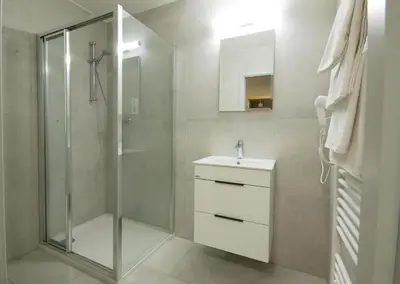 a bathroom with a shower and a sink and a mirror at Adeba Hotel in Prague