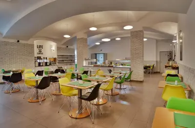 a cafeteria with tables and chairs in a cafeteria at Adeba Hotel in Prague