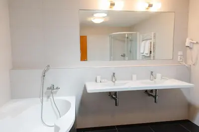 a bathroom with a sink and a tub and a mirror at Adeba Hotel in Prague