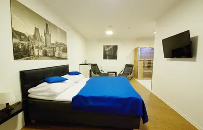 a bedroom with a bed with blue sheets and a tv at Adeba Hotel in Prague
