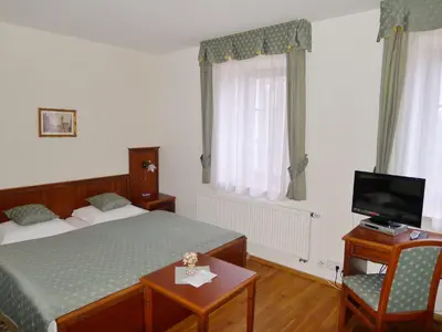 a bedroom with two beds and a mirror and a window at Hotel Nosal in Prague